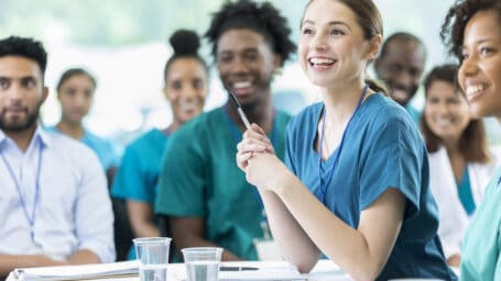 Cheerful Hispanic female nursing students smiles as she listens to a professor's lecture.